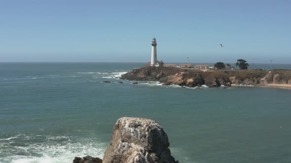 Aerial of Pigeon Point Lighthouse flying over rocks on Pacific Coast Highway near Half Moon Bay on C
