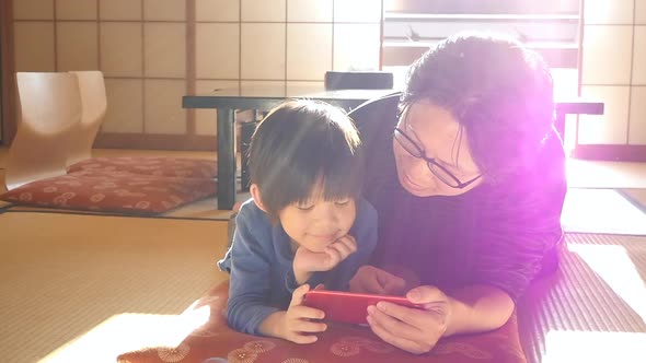 Asian Father And Son Are Using Smartphones While Spending Time Together At Home