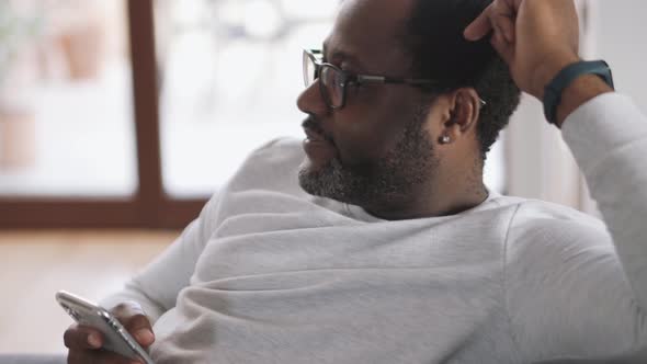 Happy African man watching TV with phone in his hand