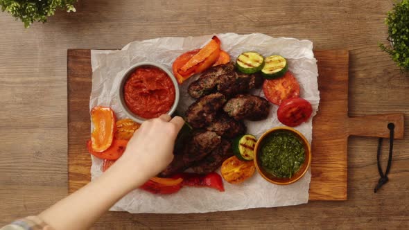 Crop person garnishing baked meat and vegetables