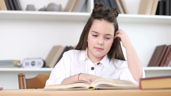 A little girl reads a book in the library