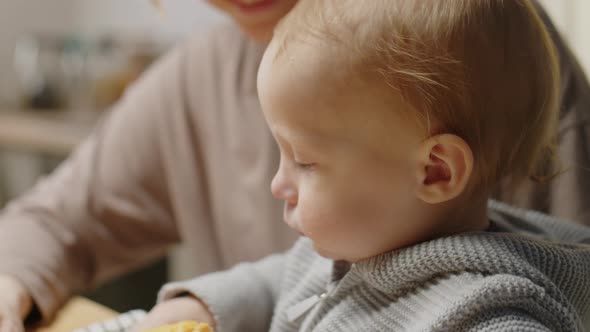 Baby Eating Puff Pastry at Kitchen Table with Loving Mom