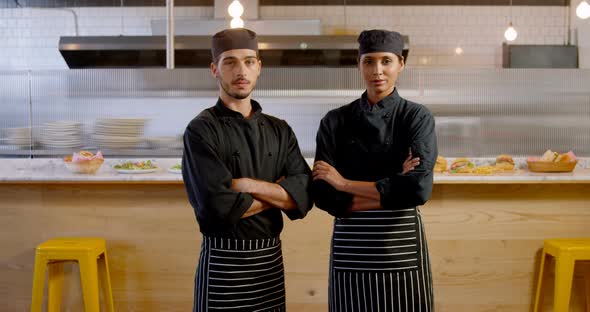 Male and female chef standing with arm crossed in caferia 4k
