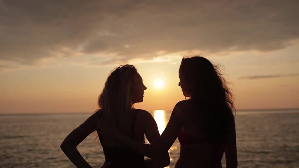 Silhouette of Couple Friends at Sea in Golden and Beautiful Sunset