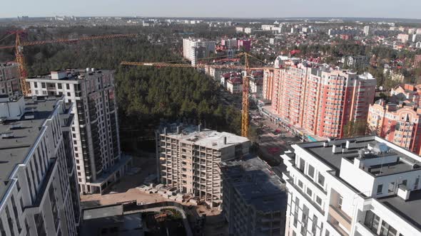 Aerial drone view of construction site with high tower crane at residential building complex.