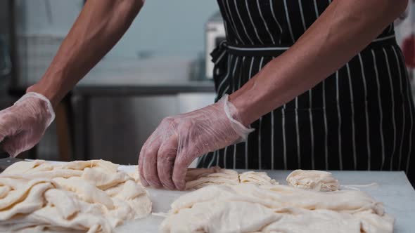 Man Cutting Stretching Cheese on the Board on Small Pieces