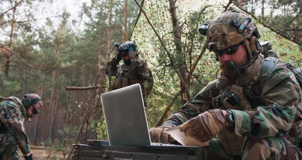 A Bearded Brigade Commander in a Military Uniform with a Helmet on His Head Checks the Coordinates