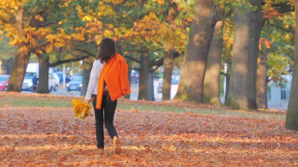 Happy Woman with Autumn Leaves Walking in Park