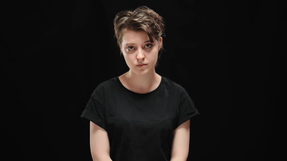 Middle Shot Portrait of Sad Humiliated Young Woman Posing at Black Background