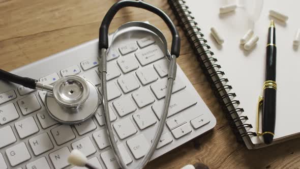 Video of close up of stethoscope with notebook and pills on wooden table