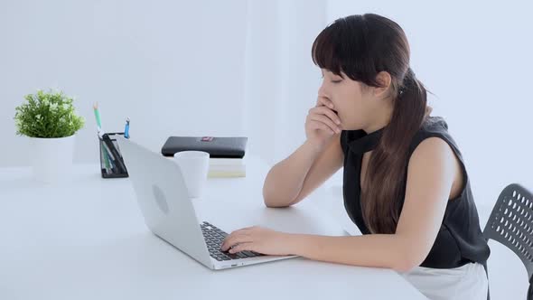 beautiful young freelance asian woman working bored and yawning on laptop computer at the office.