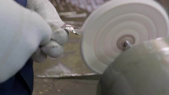 Close Up at the Hands of Worker Burnishing the Finished Silver Spoon with a Machinetool