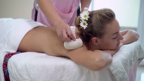 Massage Therapist Using Herbal Compress on Woman