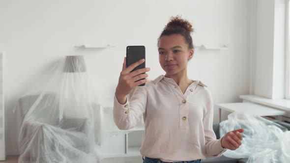 Young Woman Using Smartphone while Loader Carrying Boxes