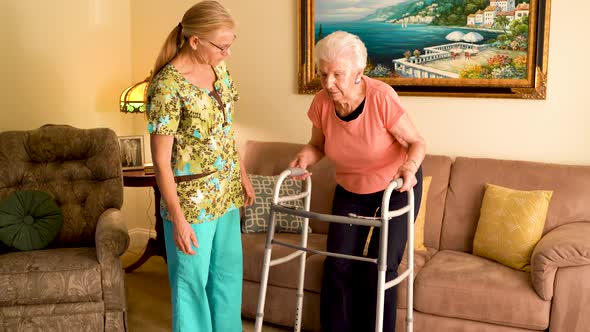 Closeup of home healthcare nurse helps elderly woman get up from couch and use a walker.