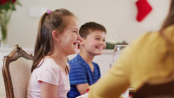 Caucasian boy and girl smiling while sitting on dining table