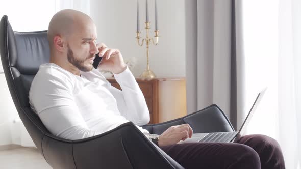 Bearded businessman working at home sitting in armchair. Business and investments concepts.