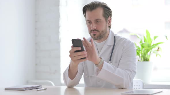 Young Doctor Using Smartphone While Sitting in Clinic