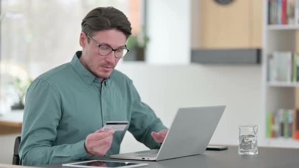 Middle Aged Man Excited By Online Shopping Success on Laptop