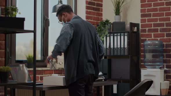 Frustrated Person with Face Mask Packing Up Office Things