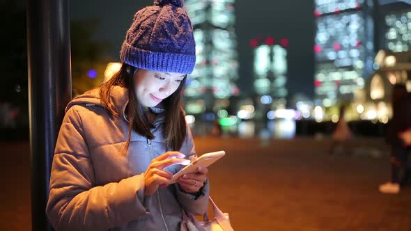 Woman using mobile phone in Yokohama city at night