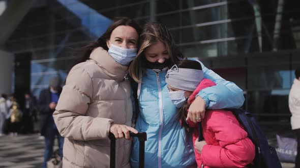 A Woman with Two Daughters Outside the Premises in Front of the Airport Terminal with Suitcases and