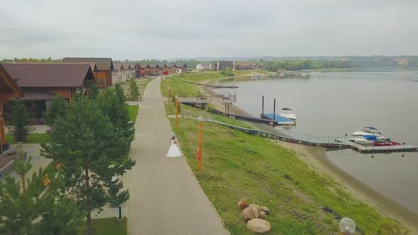 Newly Wedded Couple on Embankment Near Calm River Upper View