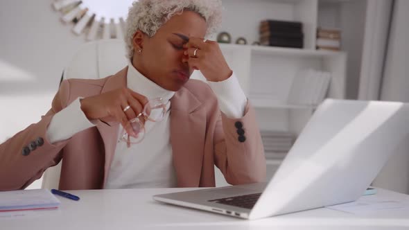 Young African American Business Woman Experiences Headaches Sits in Own Office