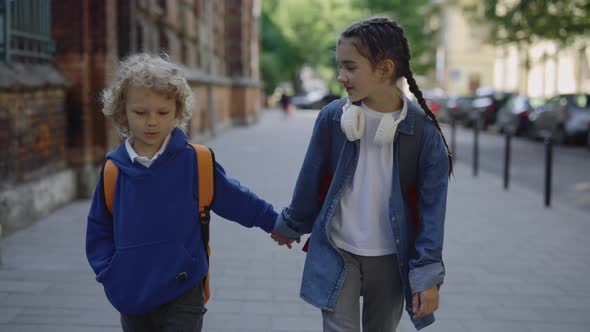 Happy Childrens with Backpacks Back to Home After Study in Elementary School Holding Hands