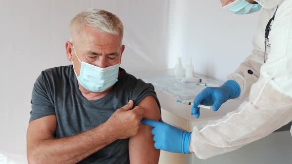 Doctor Vaccinating Senior Man In Clinic