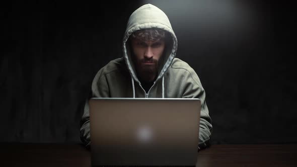 Front View of Hacker Man Hacking Online Web Site or Engaging Hacking Into Security Systems.