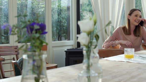 Woman Sitting at Table Talking on Phone