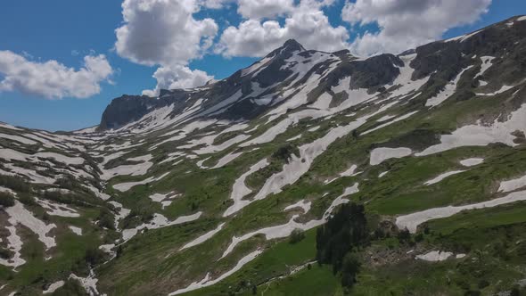 Oshten Mountain of Caucasian Range Partly Covered with Snow with Green Valley on Clear Sunny Day