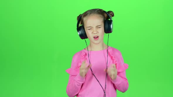 Child Listens To the Music in the Headphones. Green Screen