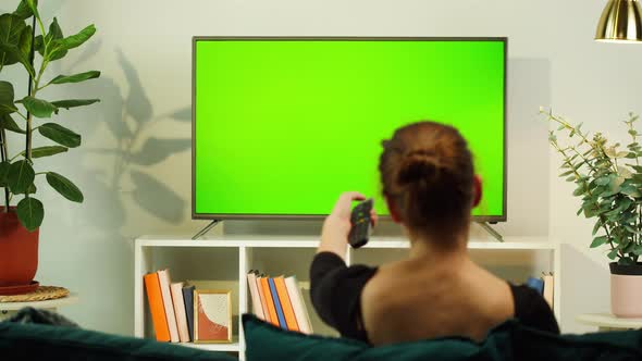 Woman Watching TV with Green Screen in Living Room Back View