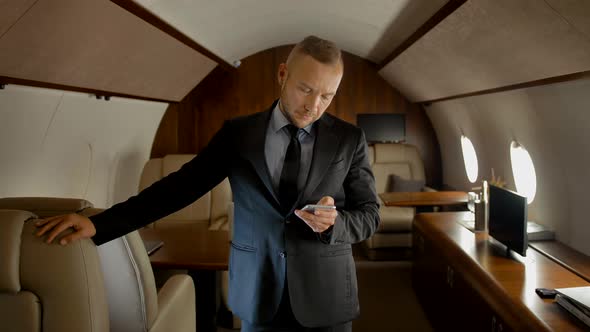 Attractive Entrepreneur with Smartphone Inside of Private Jet