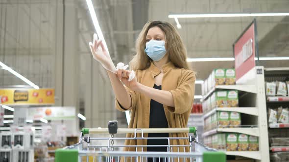 Woman in a Medical Mask Puts on Protective Rubber Gloves To Protect Against Coronavirus in a