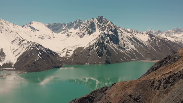 Ascending shot over reservoir in the Andes mountains showing reflection on the water-4K