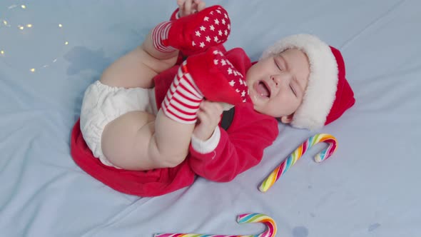 Christmas Portrait of Cute Crying Little Newborn Baby Girl Wearing Santa Hat