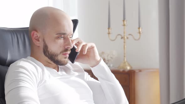 Bearded businessman working at home sitting in armchair. Business and investments concepts.