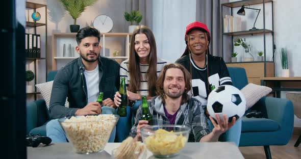 Mixed Race Friends Gathering Together at Home to Watch Sport Game on TV with Beer
