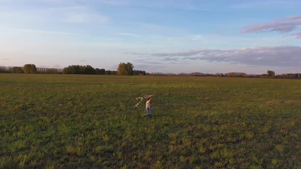 The Mother and Boy Run with a Kite on a Green Field