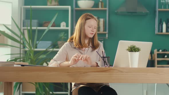 Redhaired Teenage Girl Studying at Home Online Watching a Video Tutorial