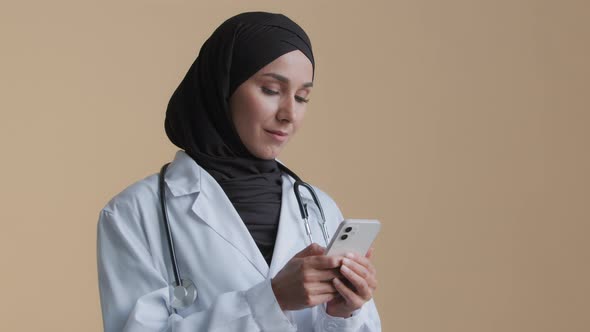 Physician Female Doctor Therapist Woman Wear Hijab White Uniform Standing in Clinic Using Smartphone