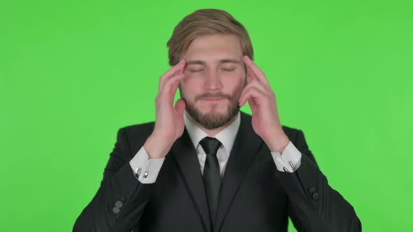 Young Businessman with Headache on Green Background