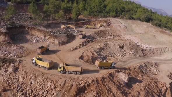 Panoramic Aerial View of Dump Trucks Driving on Quarry Road at Mountains Area