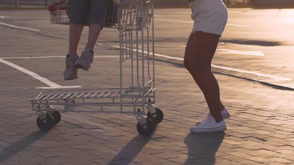 Fashion Funny Young Hipster Girls Having Fun at the Shopping Mall Parking Roll Each Other in