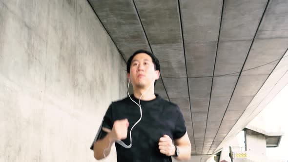 Young Asian Man Running in the City and Wearing Headphone