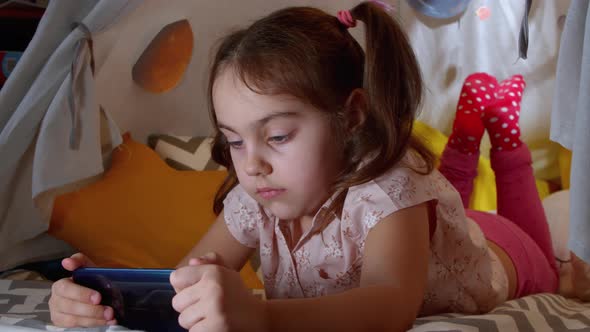 Child Plays a Game on a Smartphone with Happy Emotions