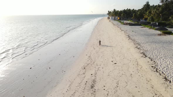 A Man Rides a Bike Along the Beach in Zanzibar Tanzania